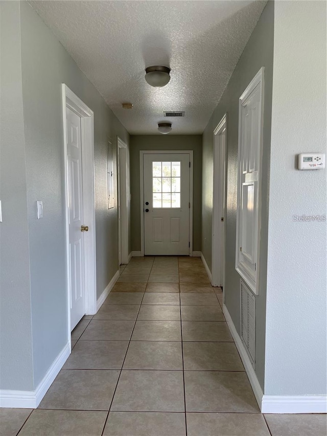 entryway featuring light tile patterned floors and a textured ceiling