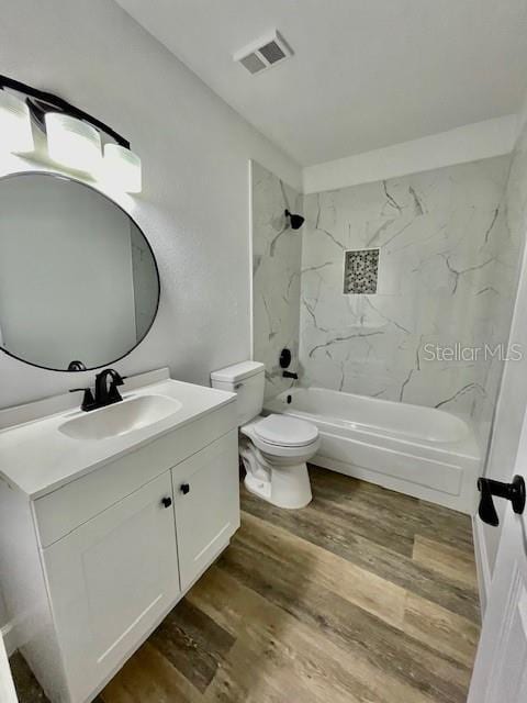 full bathroom featuring toilet, hardwood / wood-style floors, vanity, and tiled shower / bath combo