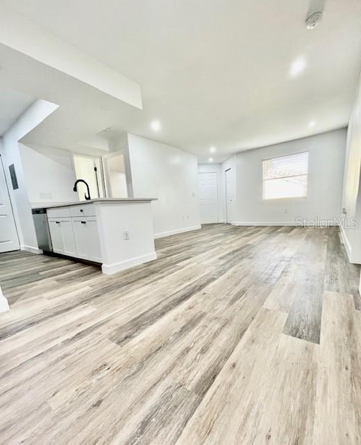 unfurnished living room featuring light wood-type flooring and sink