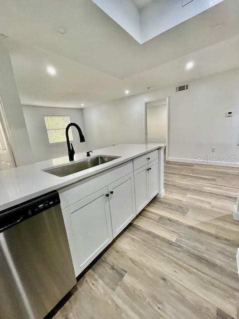 kitchen featuring white cabinets, dishwasher, light wood-type flooring, and sink