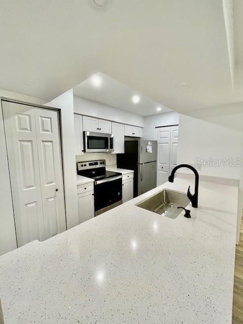 kitchen featuring light stone countertops, white cabinetry, sink, and stainless steel appliances