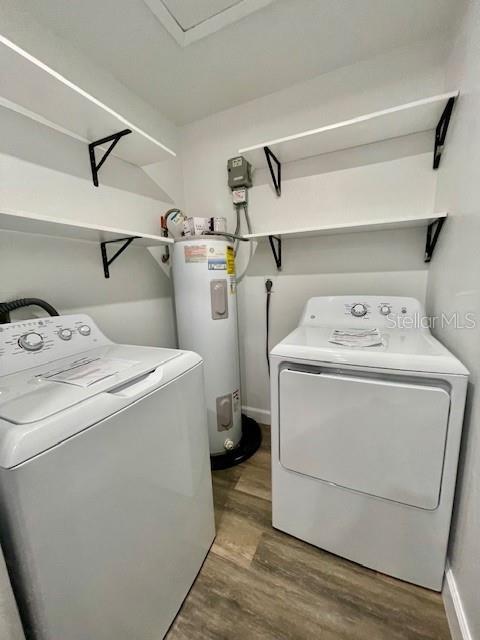 washroom featuring electric water heater, wood-type flooring, and independent washer and dryer