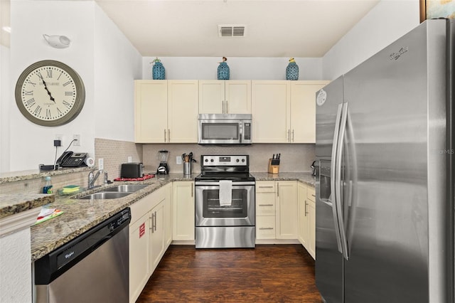 kitchen featuring light stone counters, stainless steel appliances, sink, cream cabinets, and dark hardwood / wood-style floors