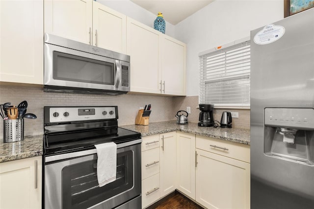 kitchen featuring cream cabinetry, light stone counters, appliances with stainless steel finishes, and tasteful backsplash