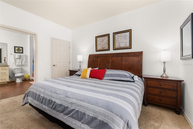 bedroom with ensuite bathroom and light colored carpet