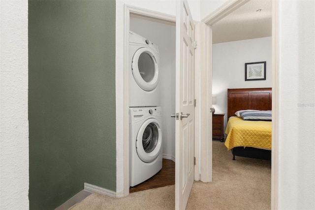 washroom with light colored carpet and stacked washer and clothes dryer