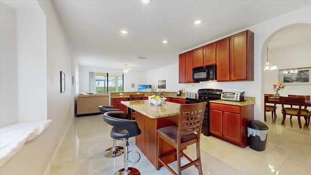 kitchen with kitchen peninsula, light stone counters, a breakfast bar, black appliances, and decorative light fixtures