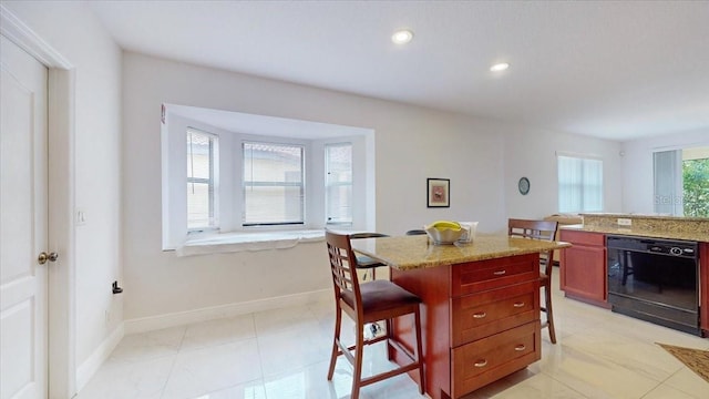 kitchen with dishwasher, a center island, a kitchen breakfast bar, and light stone counters