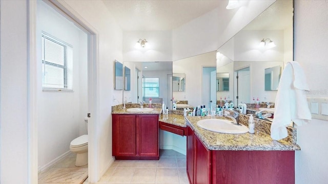 bathroom with tile patterned flooring, vanity, toilet, and a wealth of natural light