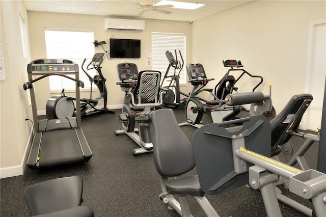 workout area with a wall mounted air conditioner, a paneled ceiling, and ceiling fan