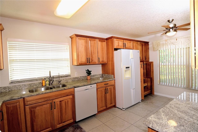 kitchen with light stone counters, white appliances, light tile patterned flooring, and sink