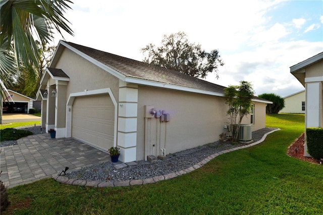 view of side of property featuring a yard, central AC unit, and a garage