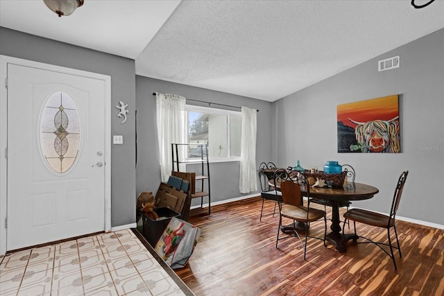 foyer entrance with a textured ceiling, hardwood / wood-style floors, and lofted ceiling