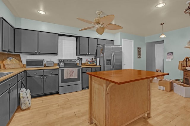 kitchen featuring light hardwood / wood-style flooring, wooden counters, pendant lighting, decorative backsplash, and appliances with stainless steel finishes