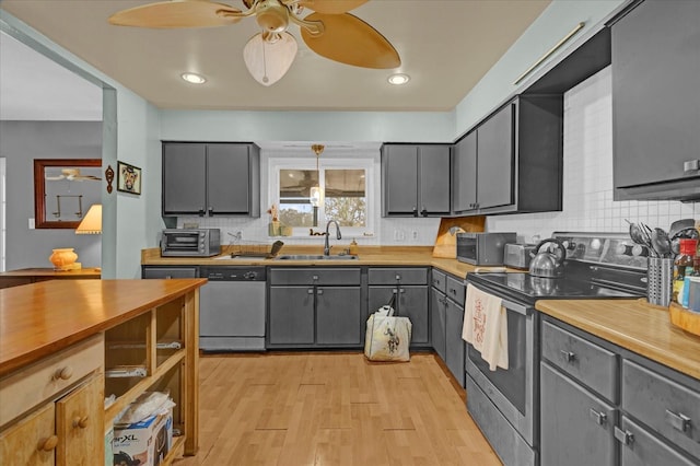 kitchen with gray cabinetry, sink, stainless steel appliances, tasteful backsplash, and light wood-type flooring