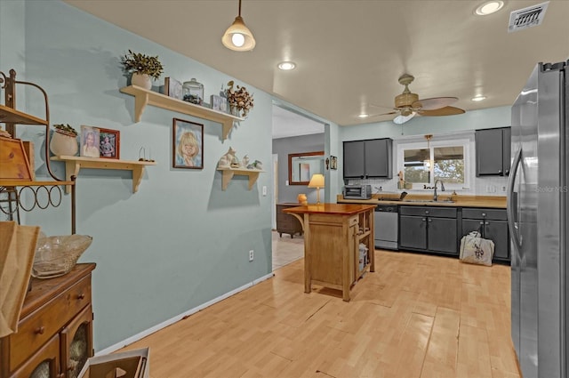 kitchen with wooden counters, stainless steel appliances, ceiling fan, sink, and light hardwood / wood-style flooring