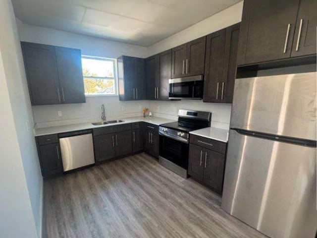 kitchen featuring dark brown cabinetry, sink, light hardwood / wood-style floors, and appliances with stainless steel finishes