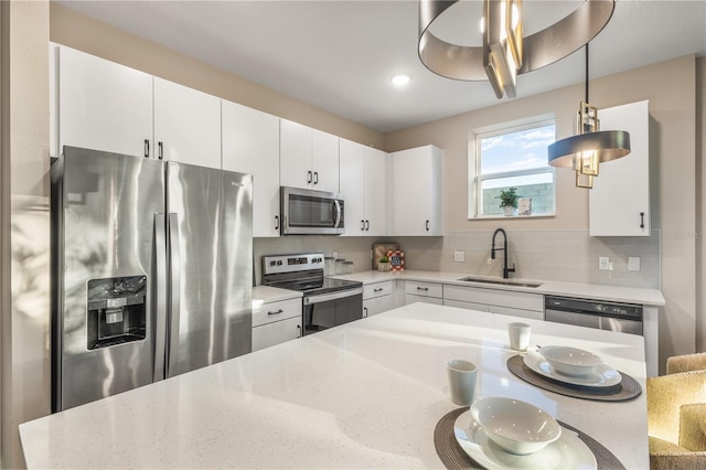 kitchen featuring white cabinetry, sink, stainless steel appliances, backsplash, and decorative light fixtures