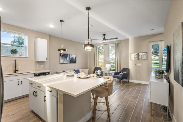 kitchen with wood-type flooring, white cabinetry, a healthy amount of sunlight, and sink