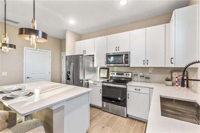 1800 Houston St, Kissimmee, FL 34743 - kitchen with appliances with stainless steel finishes, light countertops, light wood-style floors, decorative backsplash, and white cabinets