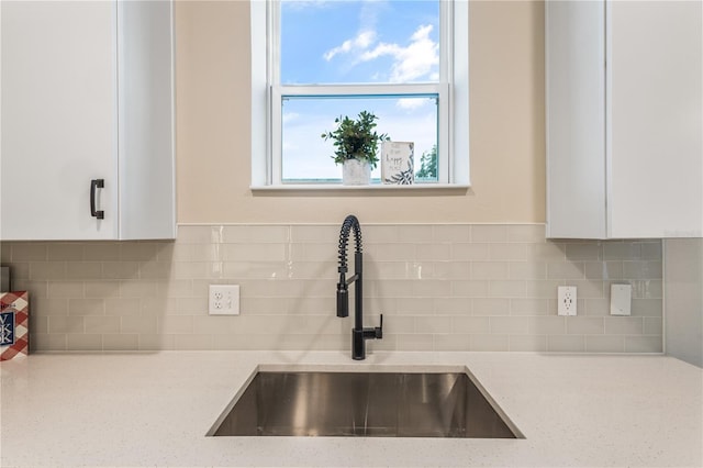 details with white cabinets, tasteful backsplash, light stone countertops, and sink