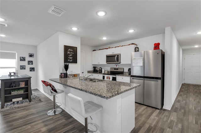 kitchen with kitchen peninsula, sink, white cabinetry, appliances with stainless steel finishes, and a breakfast bar area