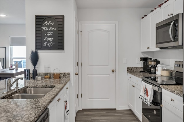 kitchen with stone counters, sink, white cabinetry, dark wood-type flooring, and appliances with stainless steel finishes