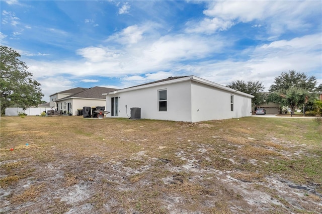 rear view of property featuring a lawn and central AC