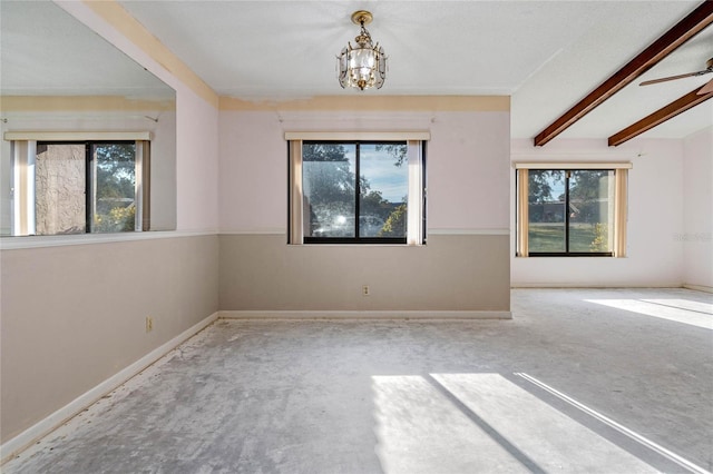 spare room with ceiling fan with notable chandelier, beam ceiling, and a wealth of natural light