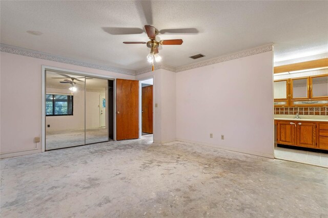 unfurnished bedroom featuring a textured ceiling, a closet, ceiling fan, and sink