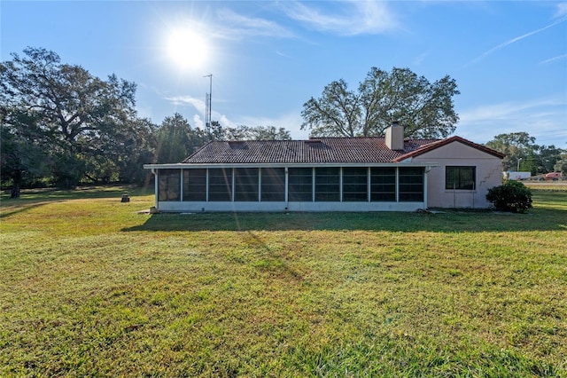 rear view of property featuring a sunroom and a yard