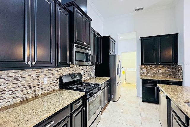 kitchen featuring visible vents, washing machine and clothes dryer, stainless steel appliances, crown molding, and dark cabinets