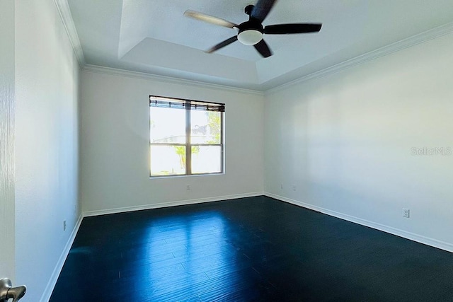 spare room featuring baseboards, dark wood finished floors, ornamental molding, a raised ceiling, and a ceiling fan