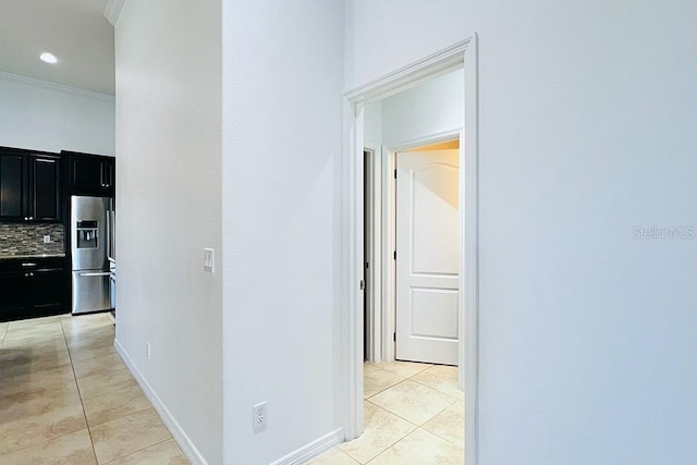 hall with light tile patterned floors, baseboards, and ornamental molding