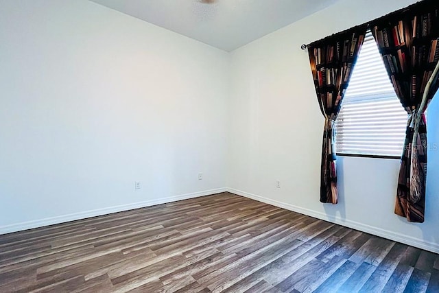 spare room with baseboards and wood finished floors