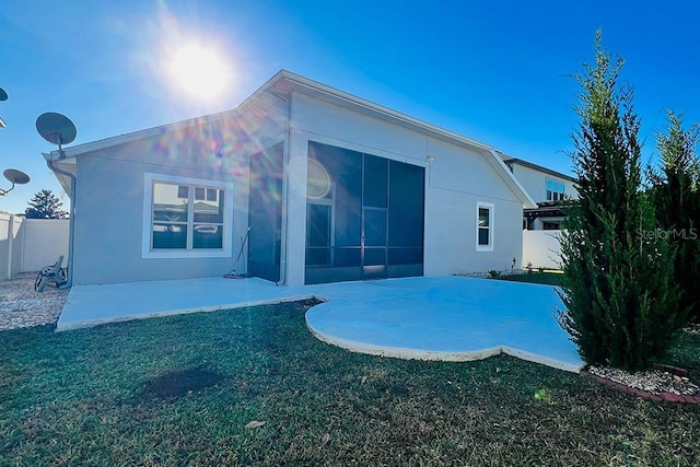 rear view of house featuring stucco siding, a fenced backyard, a yard, a sunroom, and a patio area