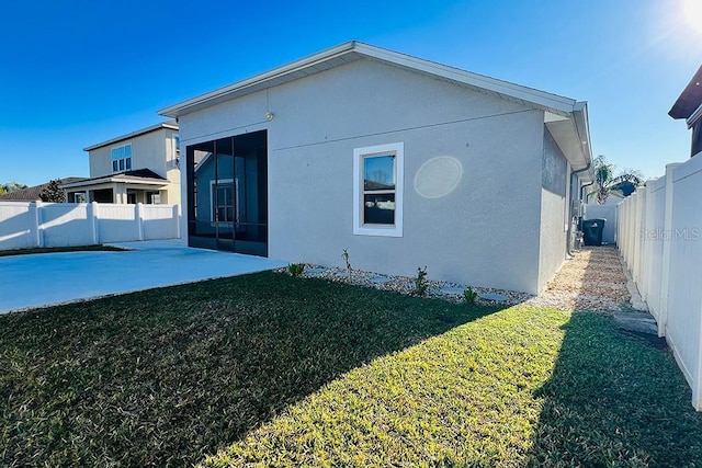 rear view of property featuring a patio area, a lawn, a fenced backyard, and stucco siding