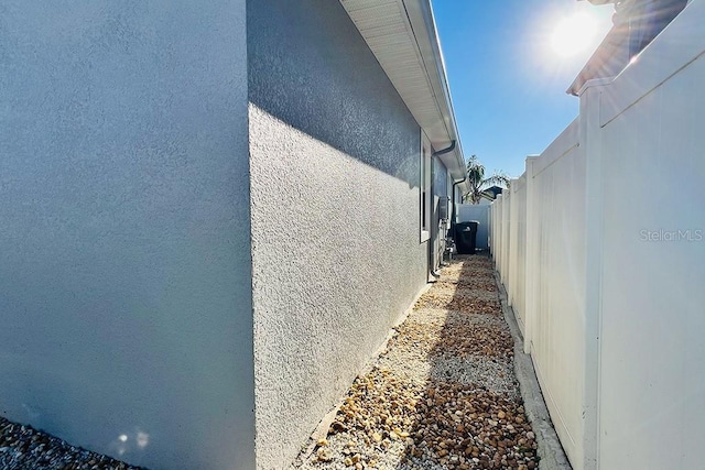 view of side of property with fence and stucco siding