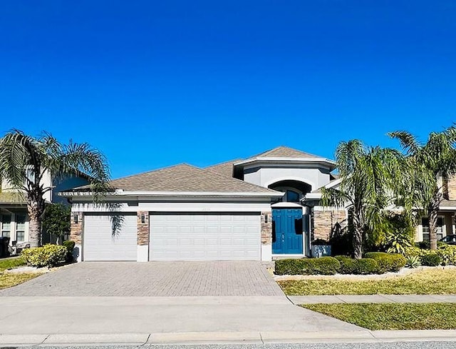 view of front of house with an attached garage, driveway, and a shingled roof