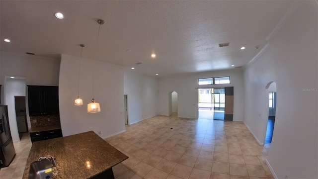 kitchen featuring dark stone counters, open floor plan, visible vents, and arched walkways