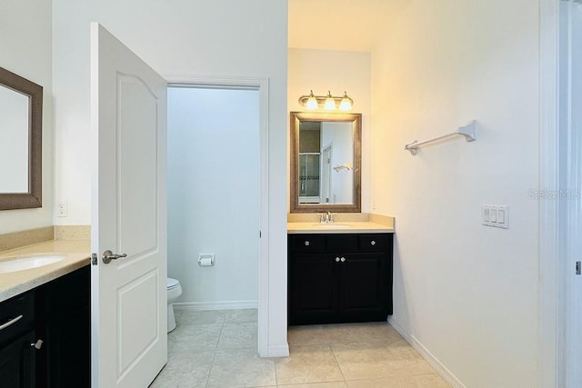 bathroom featuring tile patterned flooring, two vanities, toilet, and a sink