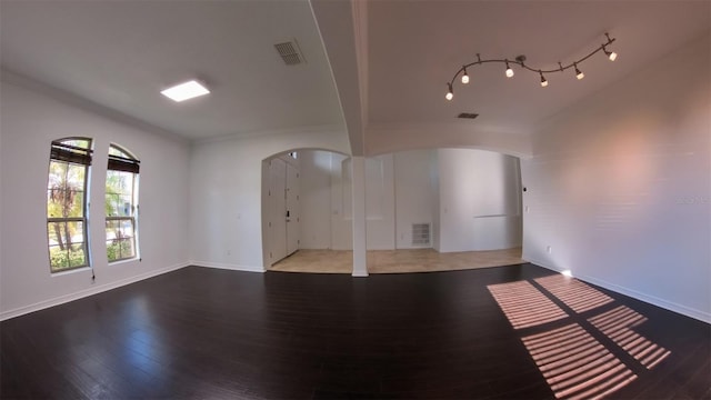 interior space featuring wood finished floors, visible vents, arched walkways, and baseboards