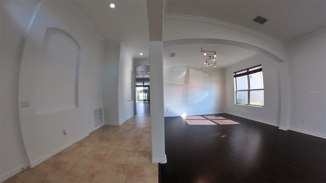 empty room with baseboards, arched walkways, visible vents, and ornamental molding