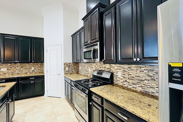 kitchen with light tile patterned floors, light stone countertops, appliances with stainless steel finishes, and dark cabinets