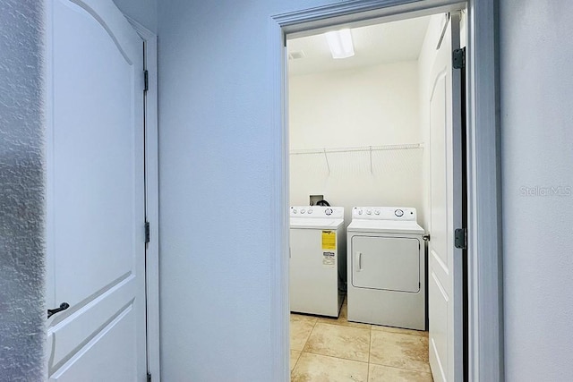 clothes washing area with laundry area, light tile patterned floors, and washer and clothes dryer