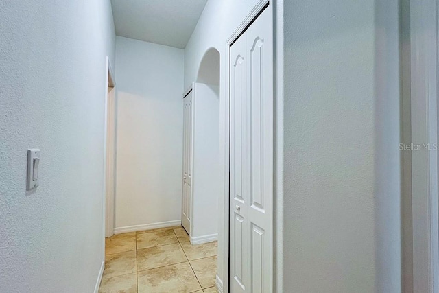 corridor with light tile patterned flooring and baseboards