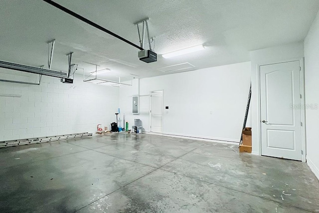 garage featuring concrete block wall, electric panel, and a garage door opener