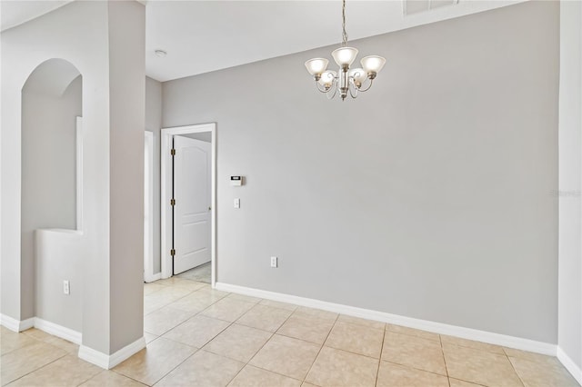 tiled spare room with a notable chandelier