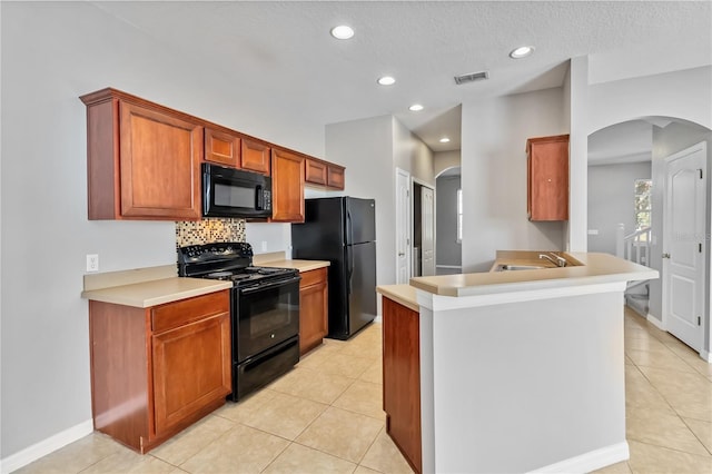 kitchen with light tile patterned floors, backsplash, and black appliances