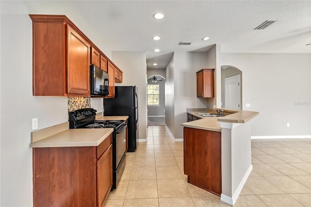 kitchen featuring sink, black appliances, a textured ceiling, light tile patterned floors, and backsplash